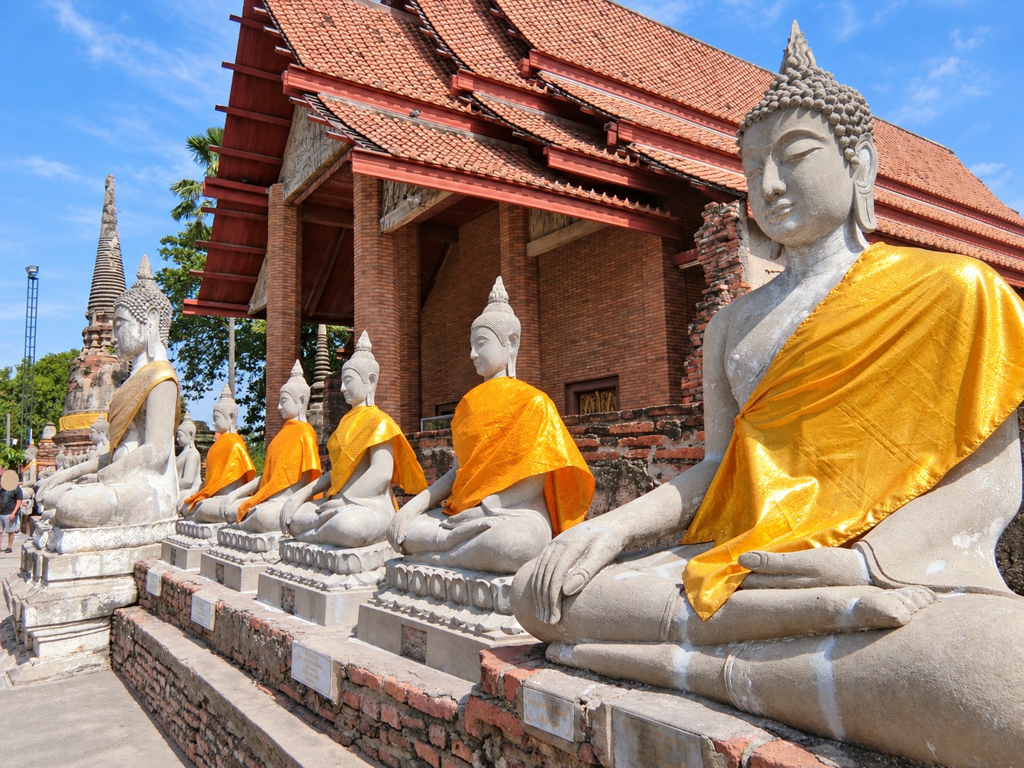 Buddha statues in gold robes beside a temple building