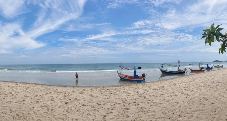 Fishing boats resting along the shore at Hua Hin beach.