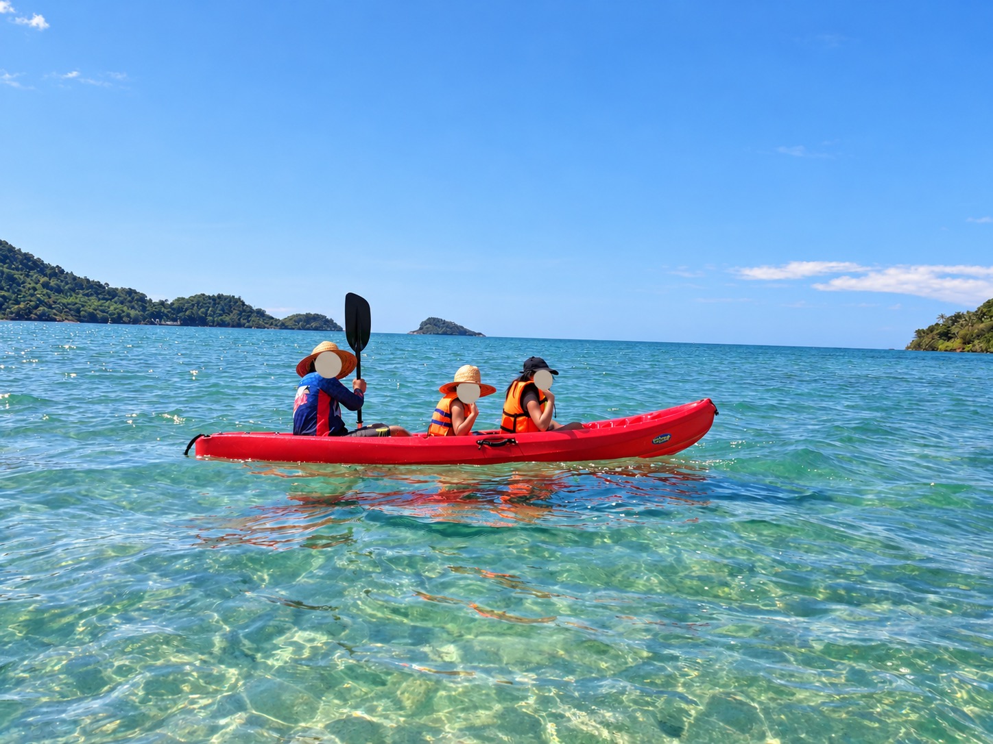 Family paddling a red kayak with faces covered
