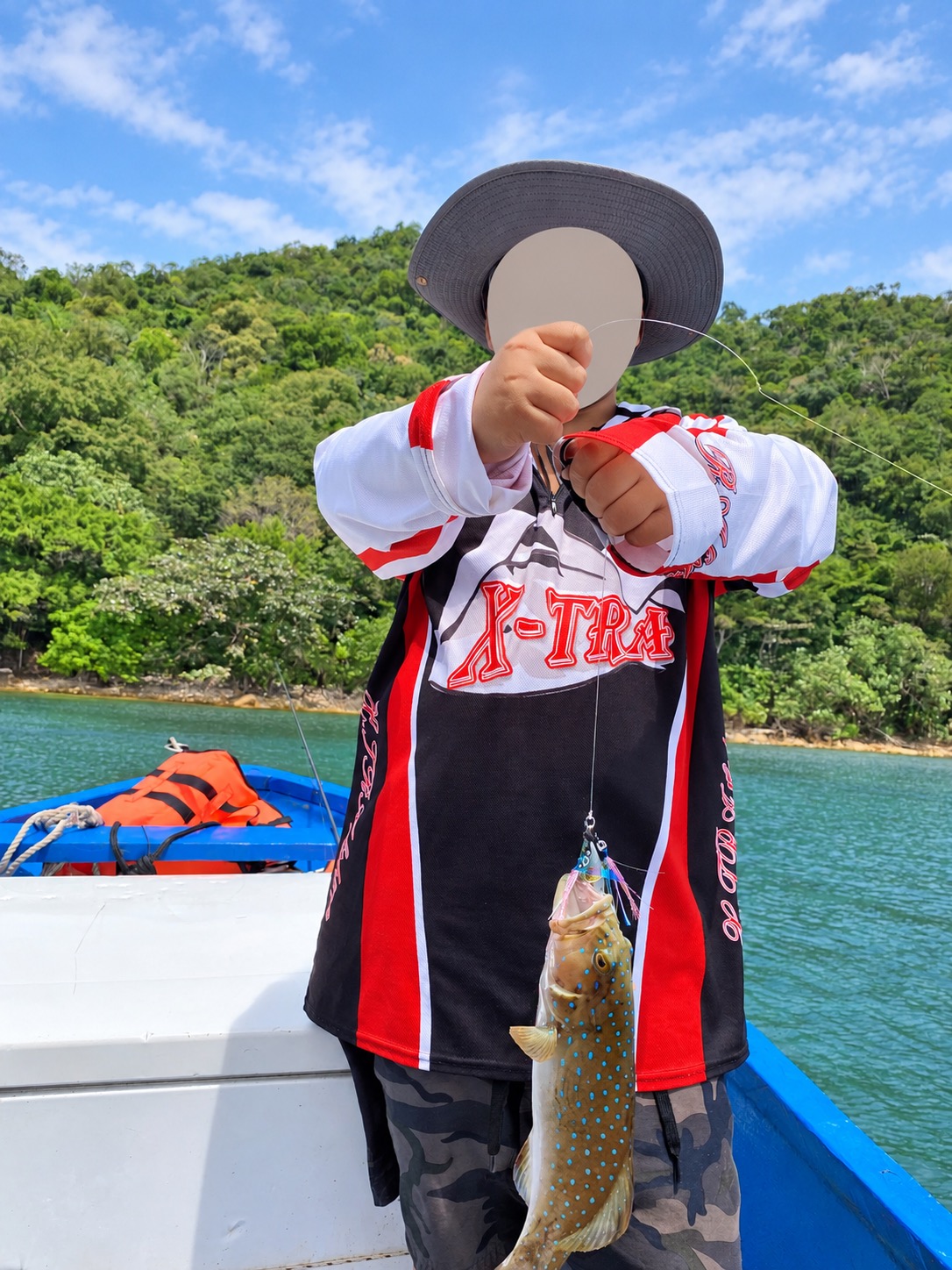 Child holding a fishing catch with face covered
