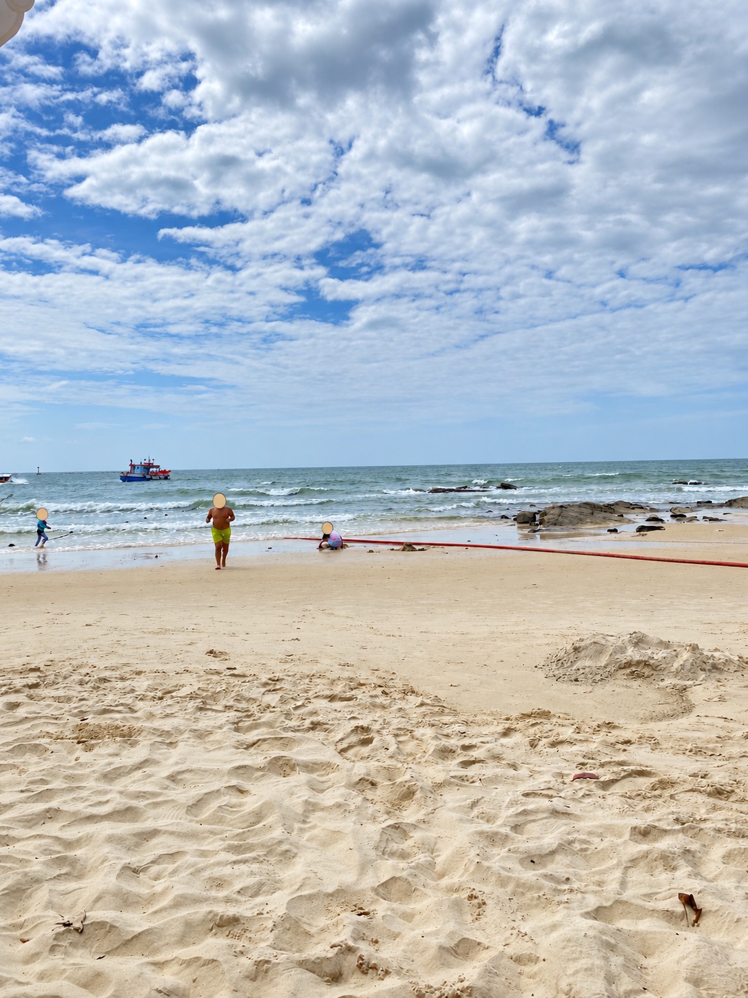 Children playing on a sandy Koh Samet beach with faces covered